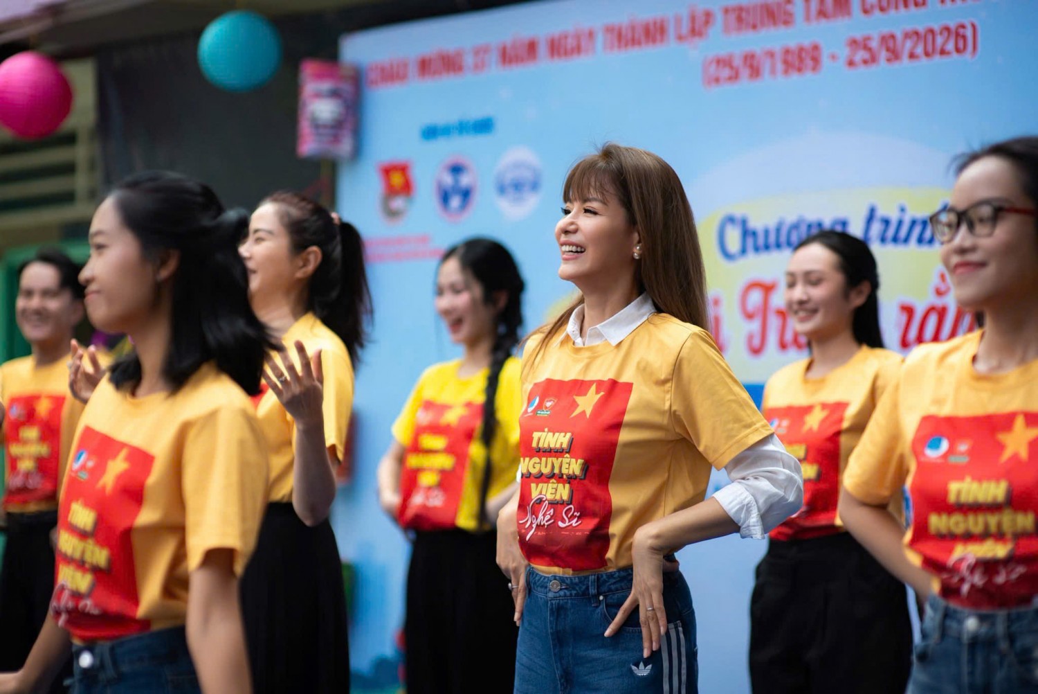Nhóm tình nguyện viên nghệ sĩ mặc áo đồng phục vàng tham gia chương trình