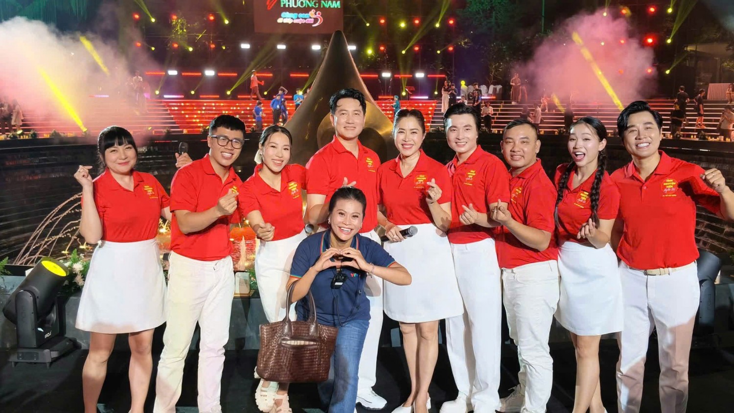 Nhóm nghệ sĩ mặc áo polo đỏ chụp ảnh kỷ niệm tại chương trình sự kiện.
