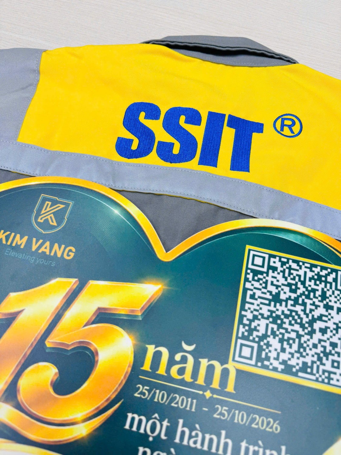 Chi tiết logo SSIT màu xanh trên nền vải vàng của đồng phục.