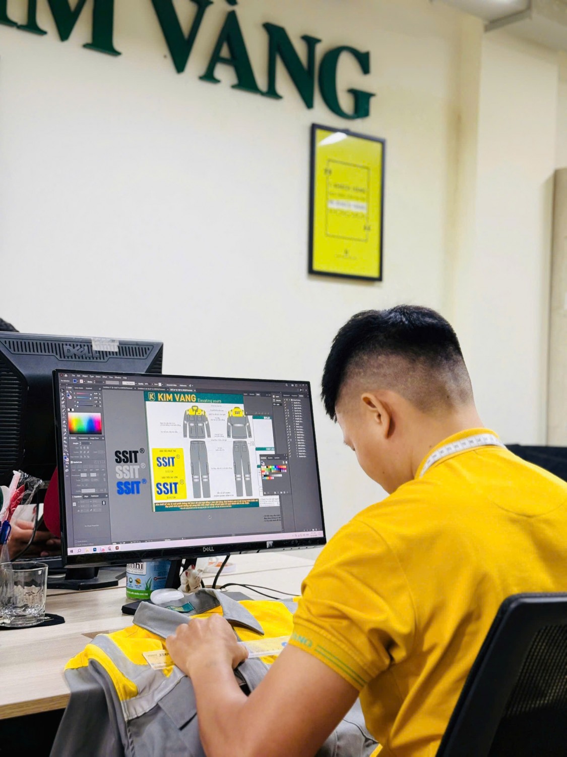 Nhân viên Kim Vàng so sánh áo bảo hộ SSIT thực tế với bản thiết kế trên máy.