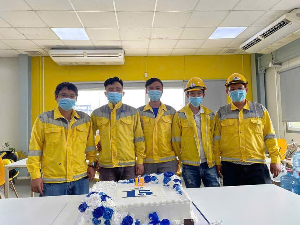 Nhân sự SSIT mặc áo bảo hộ màu vàng xám trong ảnh tập thể.