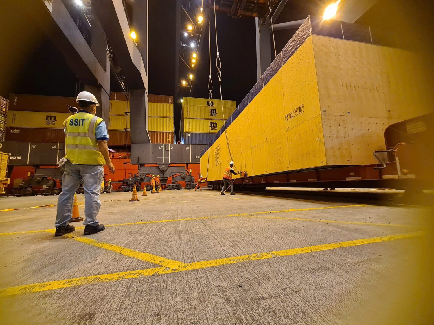 Người lao động SSIT mặc trang phục làm việc giữa các container tại cảng biển.