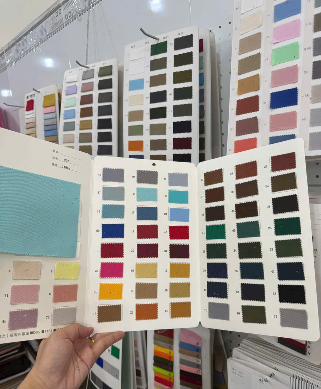 Bảng mẫu màu vải được mở để đối chiếu màu sắc khi tư vấn đồng phục.
