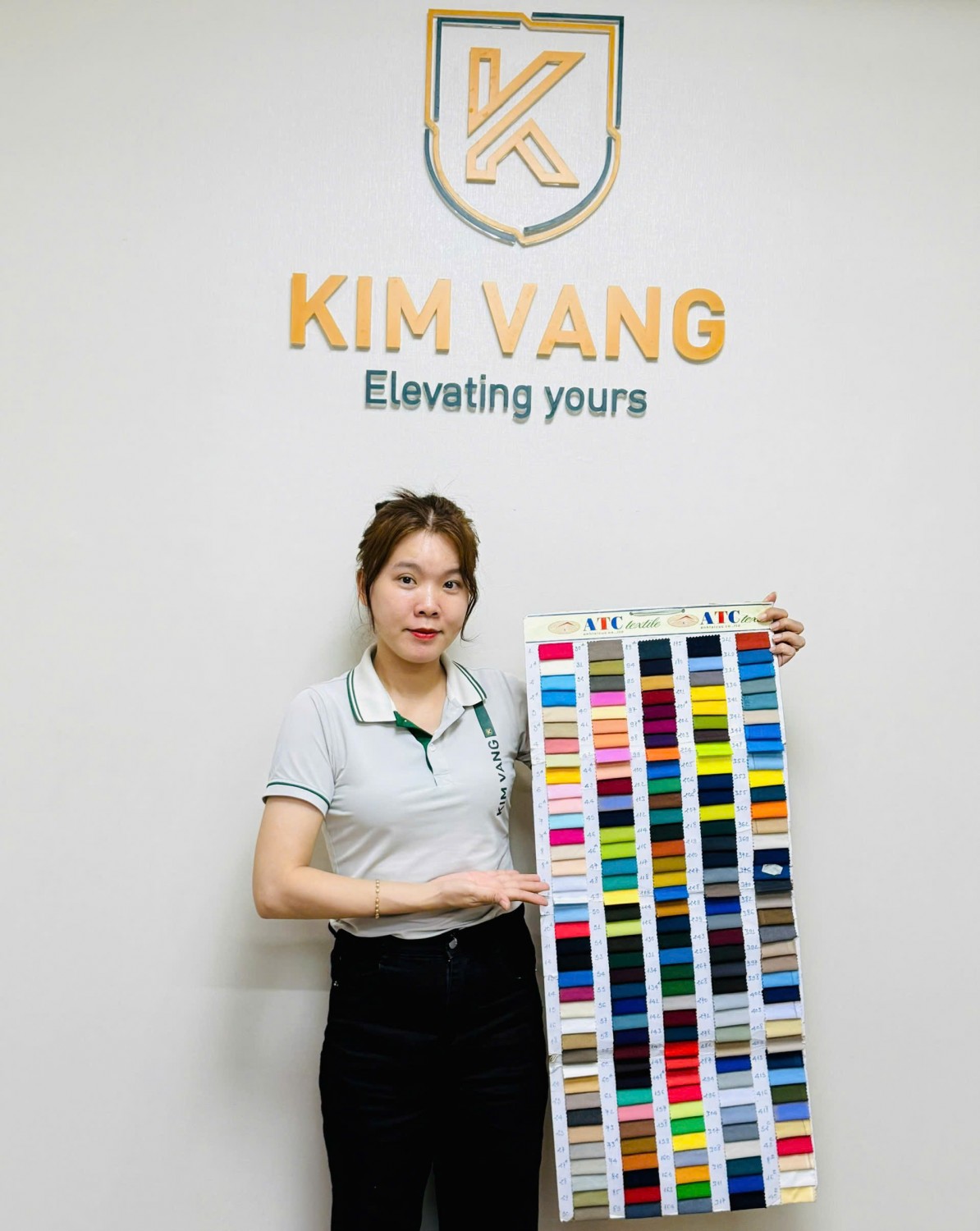 Nhân viên Kim Vàng giới thiệu bảng mẫu vải nhiều màu tại văn phòng.