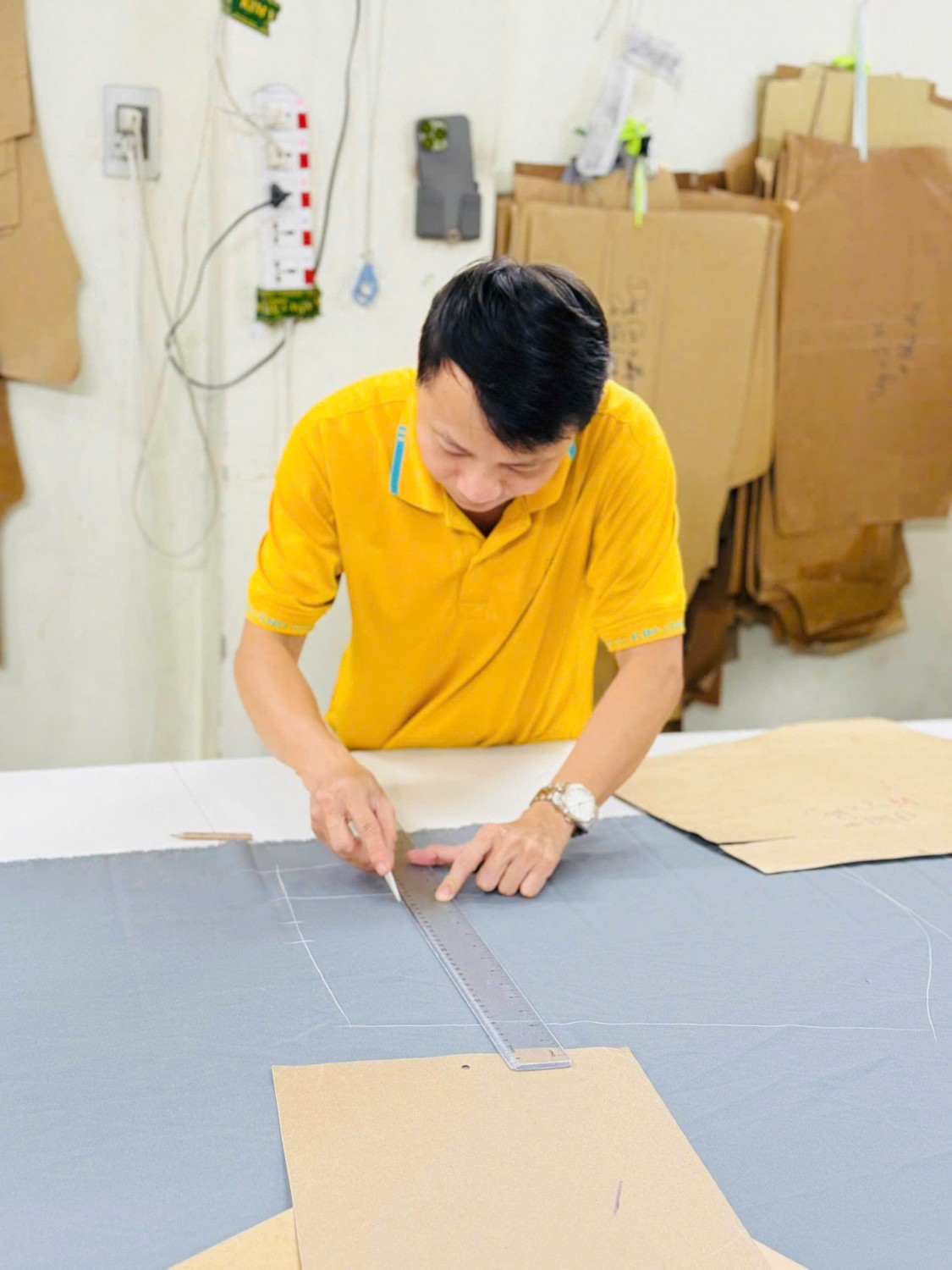 Người thợ Kim Vàng dùng thước kiểm tra và lấy dấu trên vải xám.