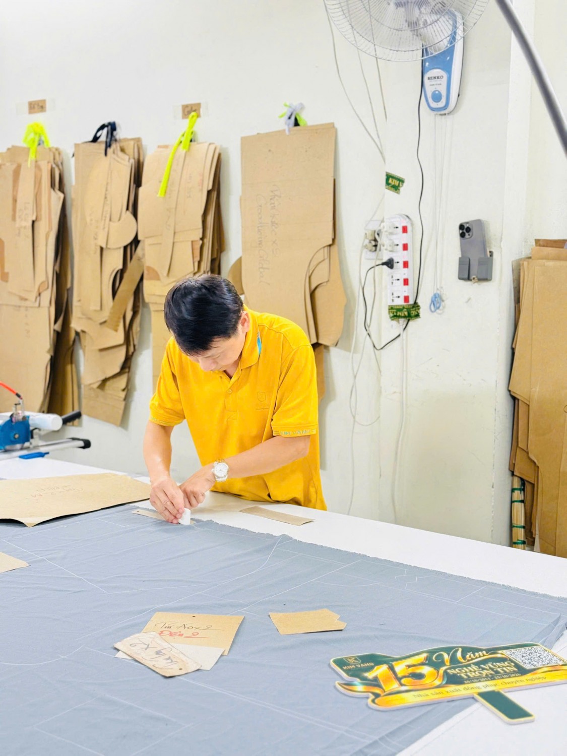 Người thợ Kim Vàng kiểm tra vị trí đánh dấu trên tấm vải trải bàn.