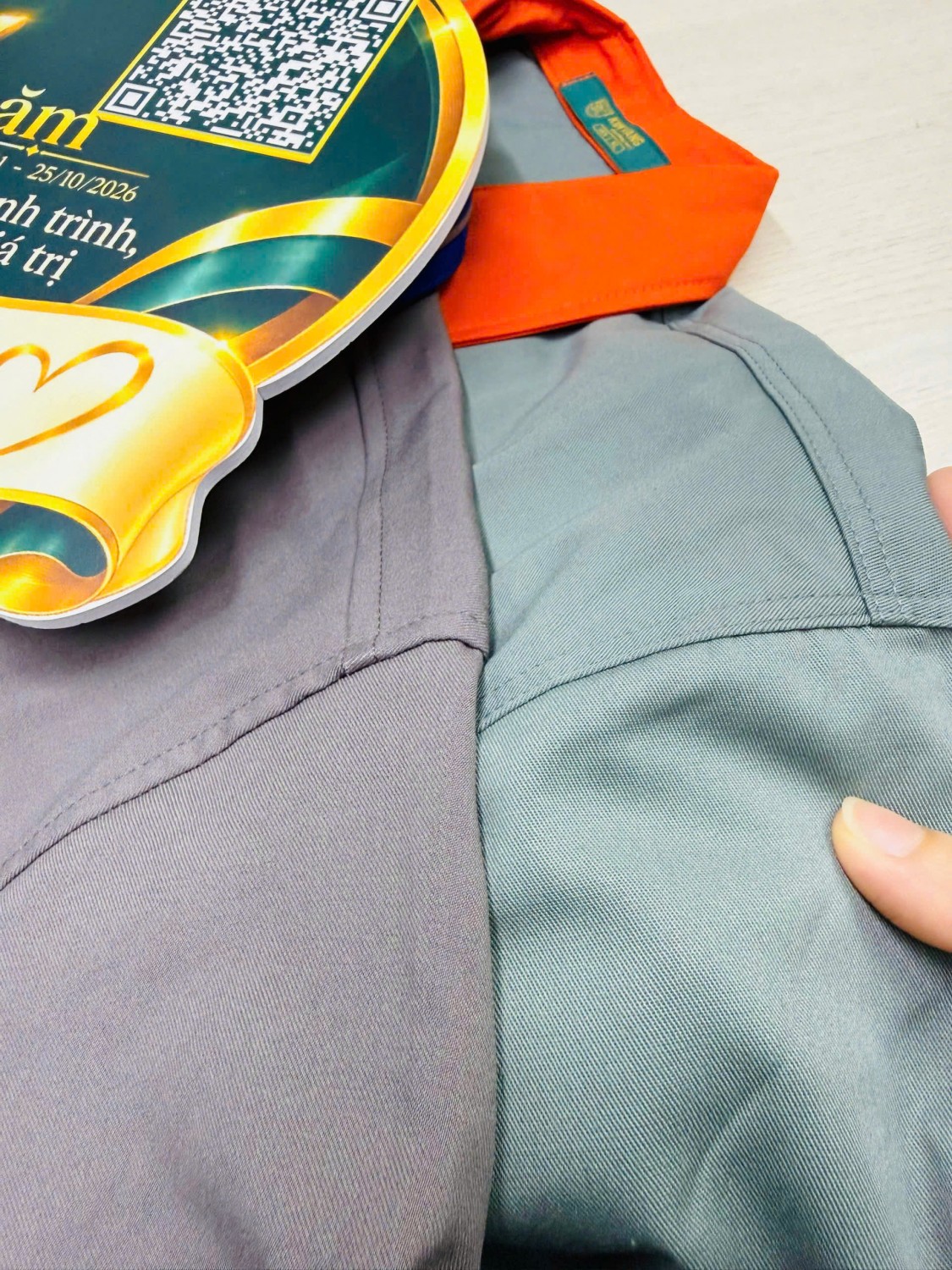 Cận cảnh đường may và mảng vải xám phối cam trên đồng phục kỹ thuật.