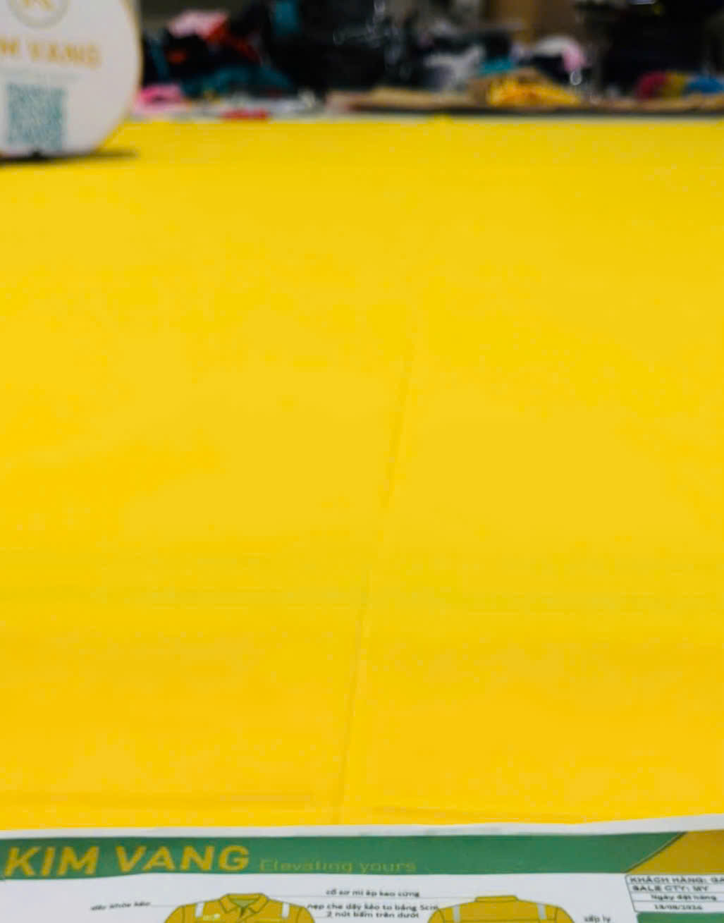 Tấm vải vàng được trải trên bàn để đối chiếu với bản thiết kế đồng phục.