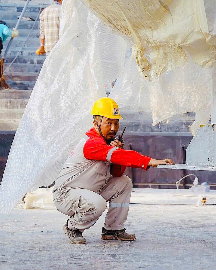 Công nhân Kiên Cường ngồi xổm làm việc trong quần bảo hộ công trường.